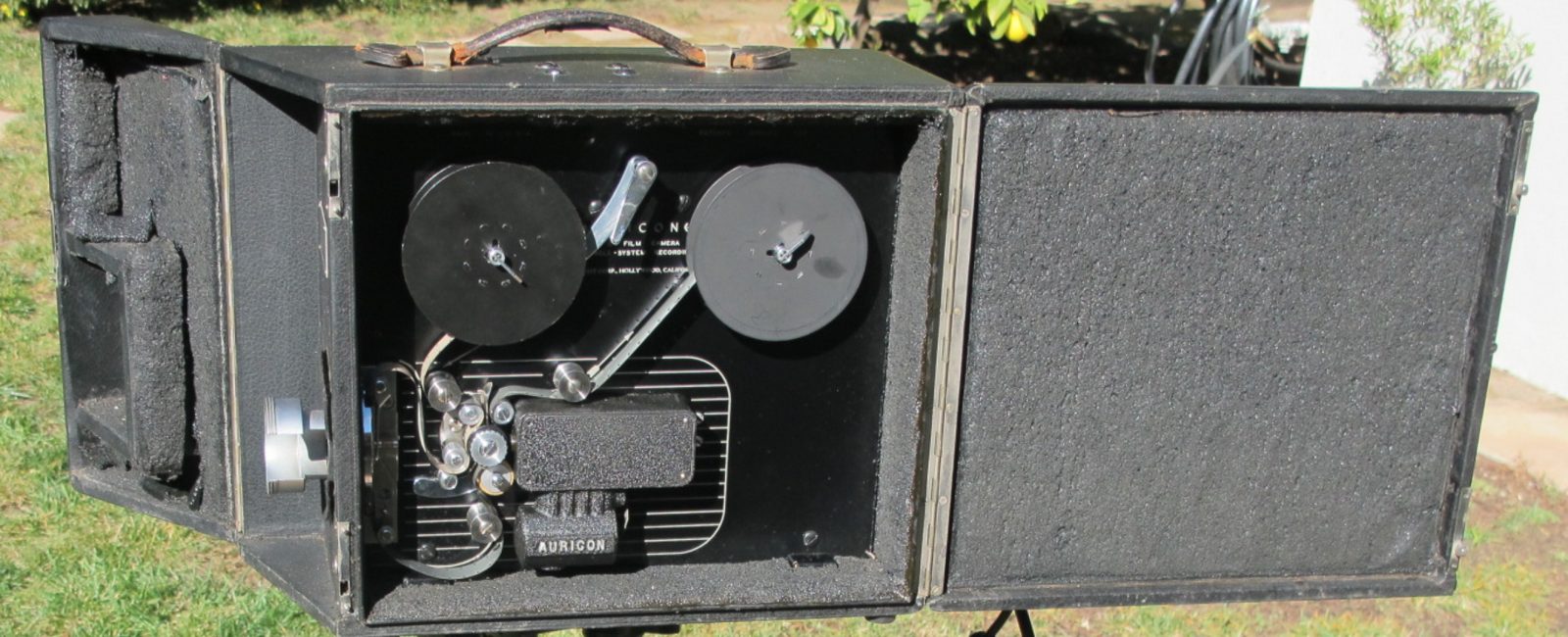 An early Auricon 16mm sound camera in its open case, showing the film path, two reels and the sound recording unit.