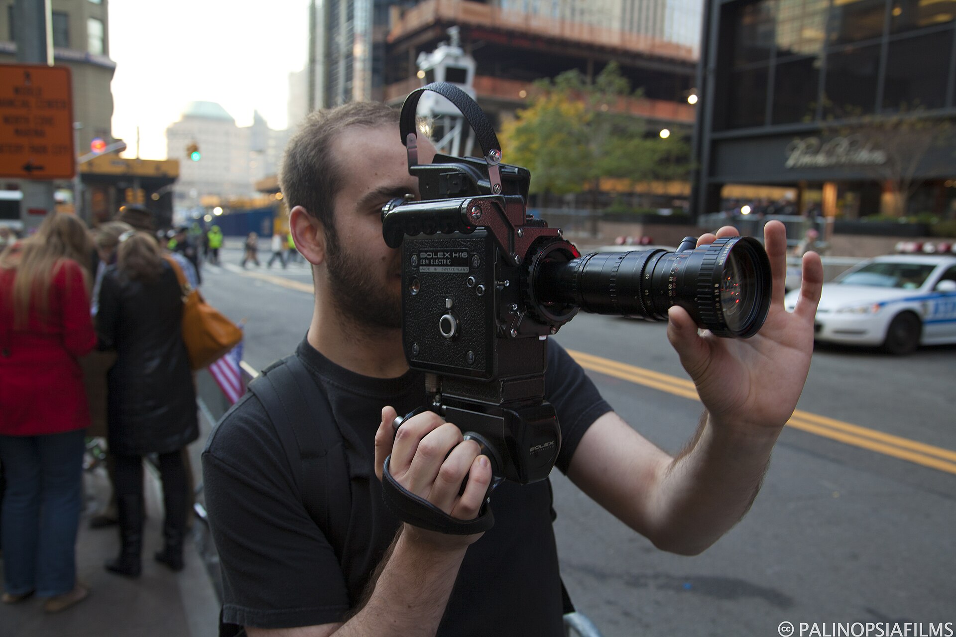 A man shooting on a city street with an electric-drive Bolex H16 EBM fitted with a long Angenieux zoom lens.